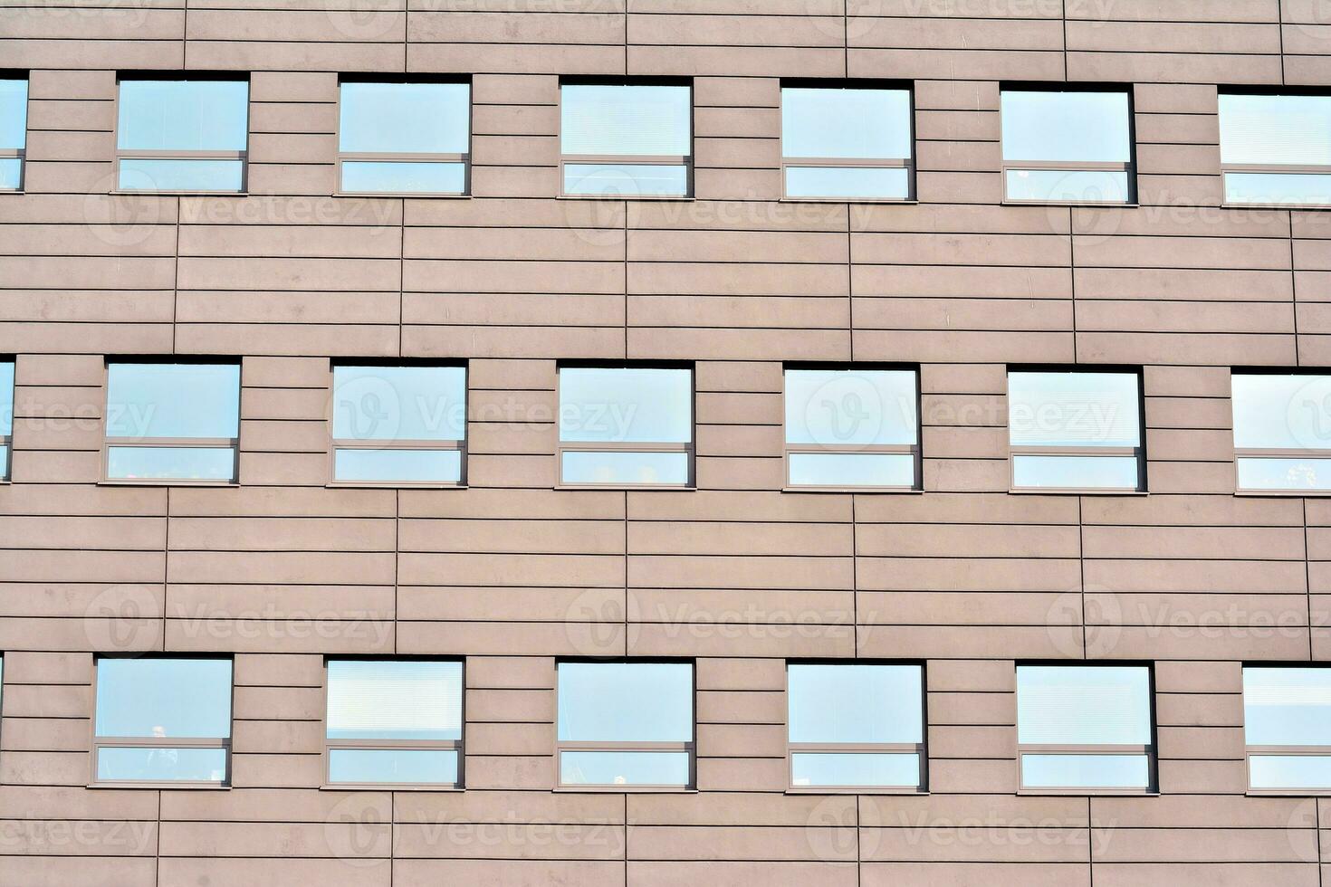 Abstract closeup of the glass-clad facade of a modern building covered in reflective plate glass. Architecture abstract background. Glass wall and facade detail. photo