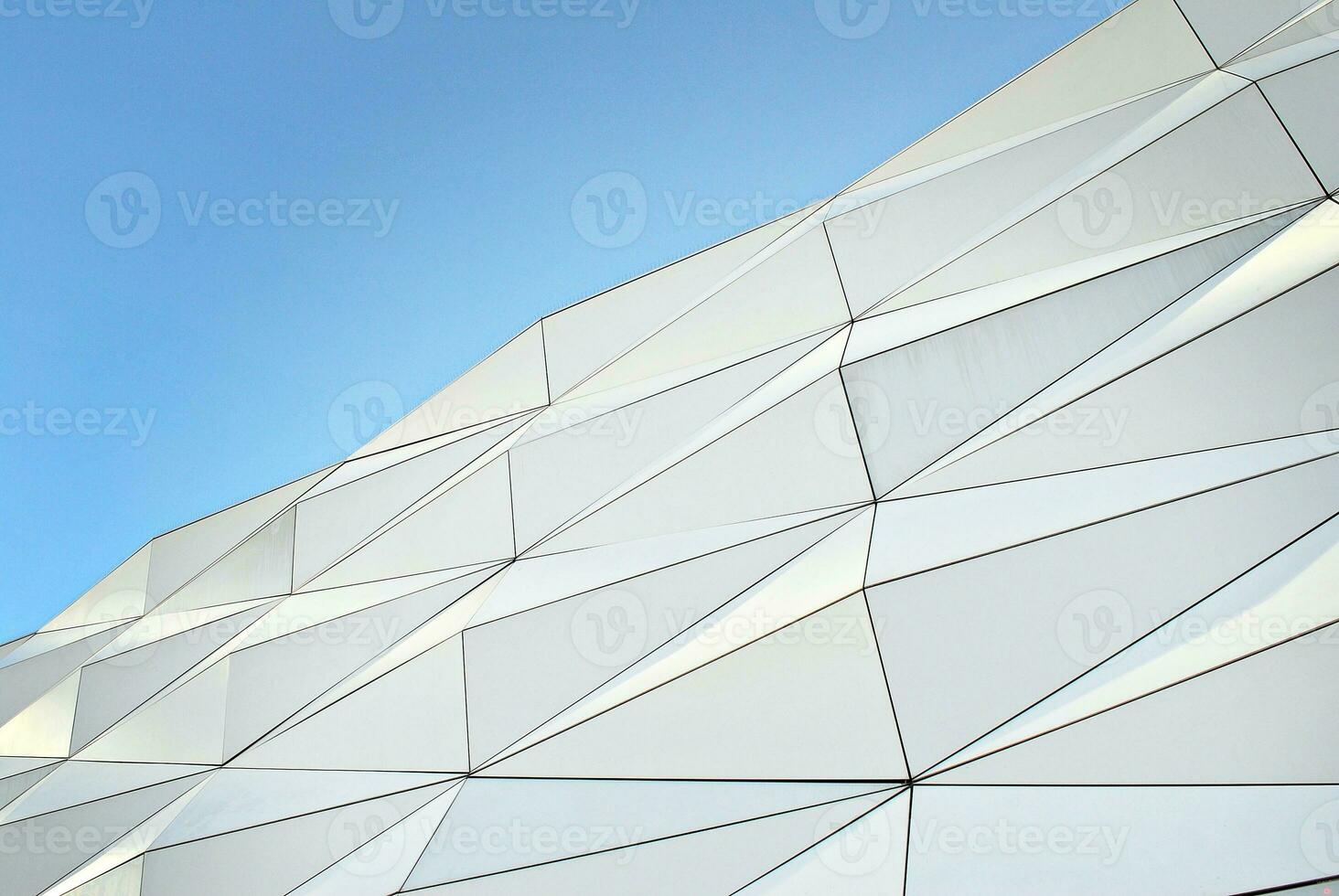 Abstract closeup of the glass-clad facade of a modern building covered in reflective plate glass. Architecture abstract background. Glass wall and facade detail. photo