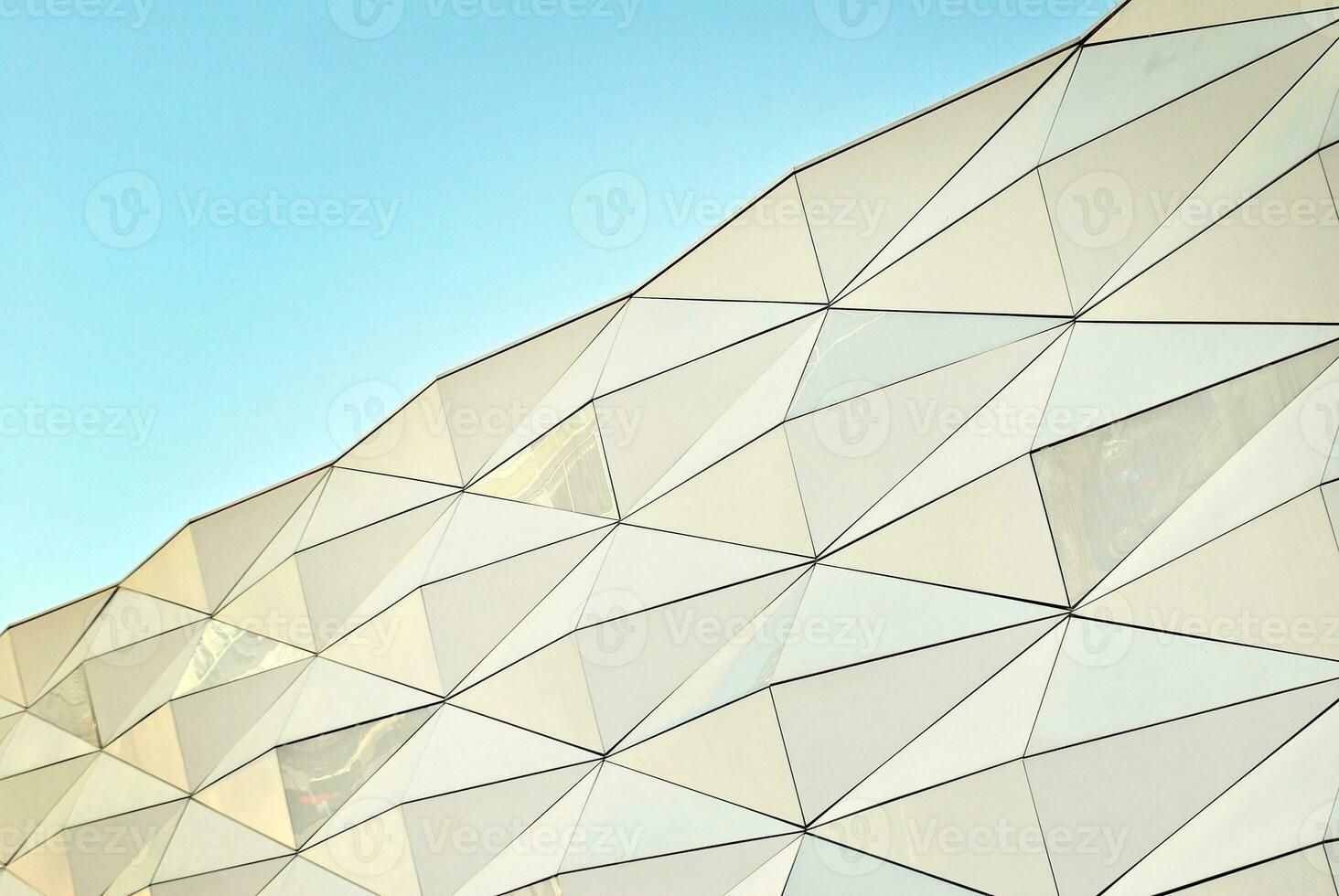 Abstract closeup of the glass-clad facade of a modern building covered in reflective plate glass. Architecture abstract background. Glass wall and facade detail. photo