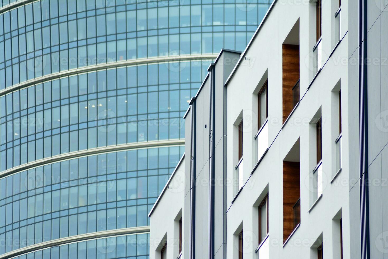 Abstract closeup of the glass-clad facade of a modern building covered in reflective plate glass. Architecture abstract background. Glass wall and facade detail. photo