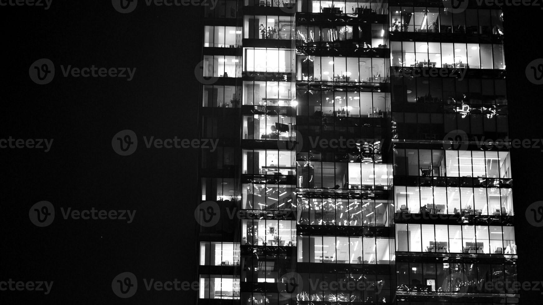 Pattern of office buildings windows illuminated at night. Glass architecture ,corporate building at night - business concept. Black and white. photo