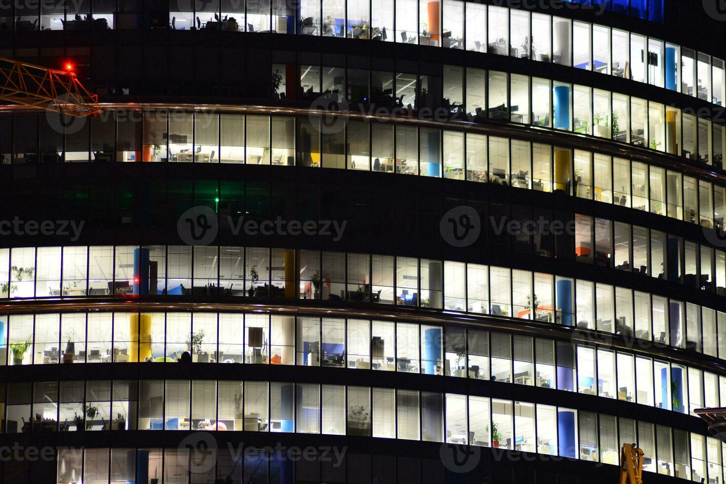 fragmento de el vaso fachada de un moderno corporativo edificio a noche. moderno vaso oficina en ciudad. grande brillante ventanas en moderno oficina edificios a noche, en filas de ventanas ligero brilla foto