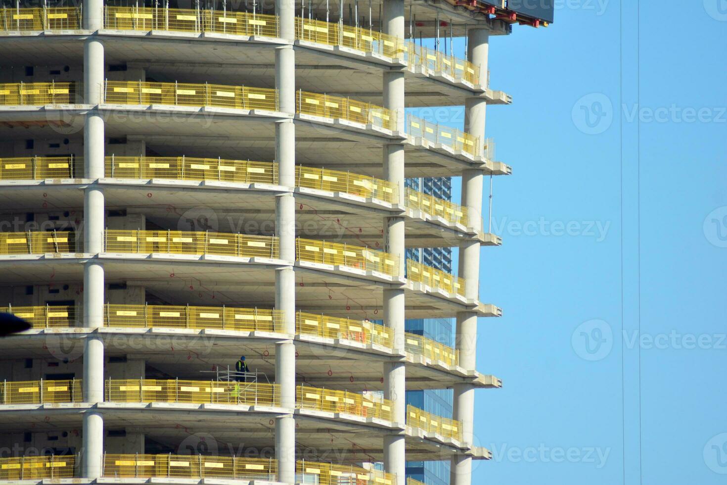 High rise building under construction. Installation of glass facade panels on a reinforced concrete structure. photo