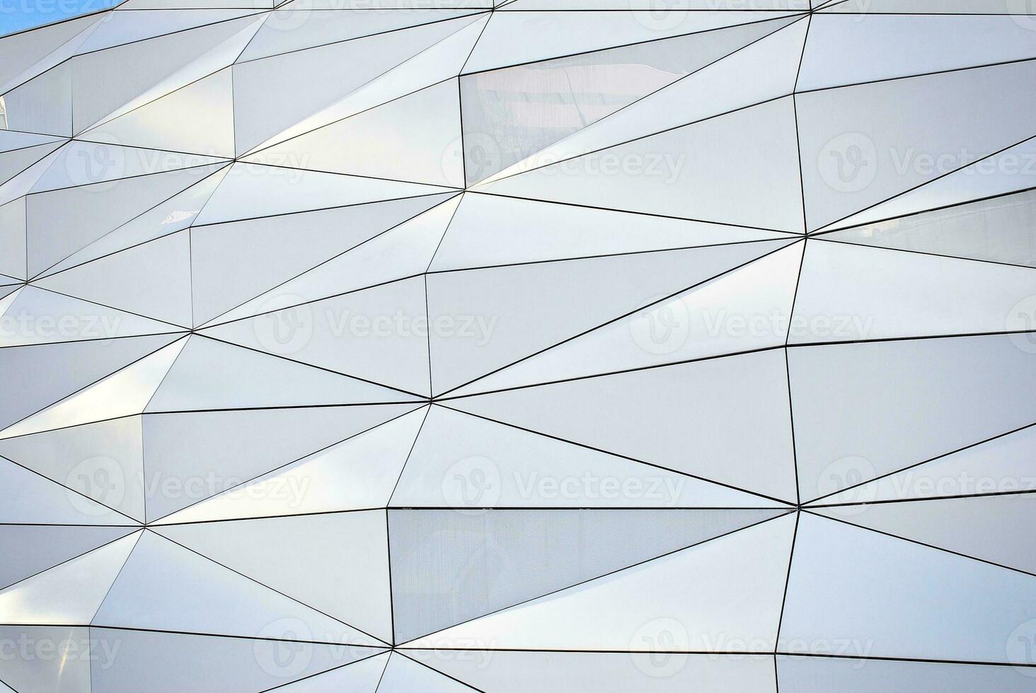 Abstract closeup of the glass-clad facade of a modern building covered in reflective plate glass. Architecture abstract background. Glass wall and facade detail. photo