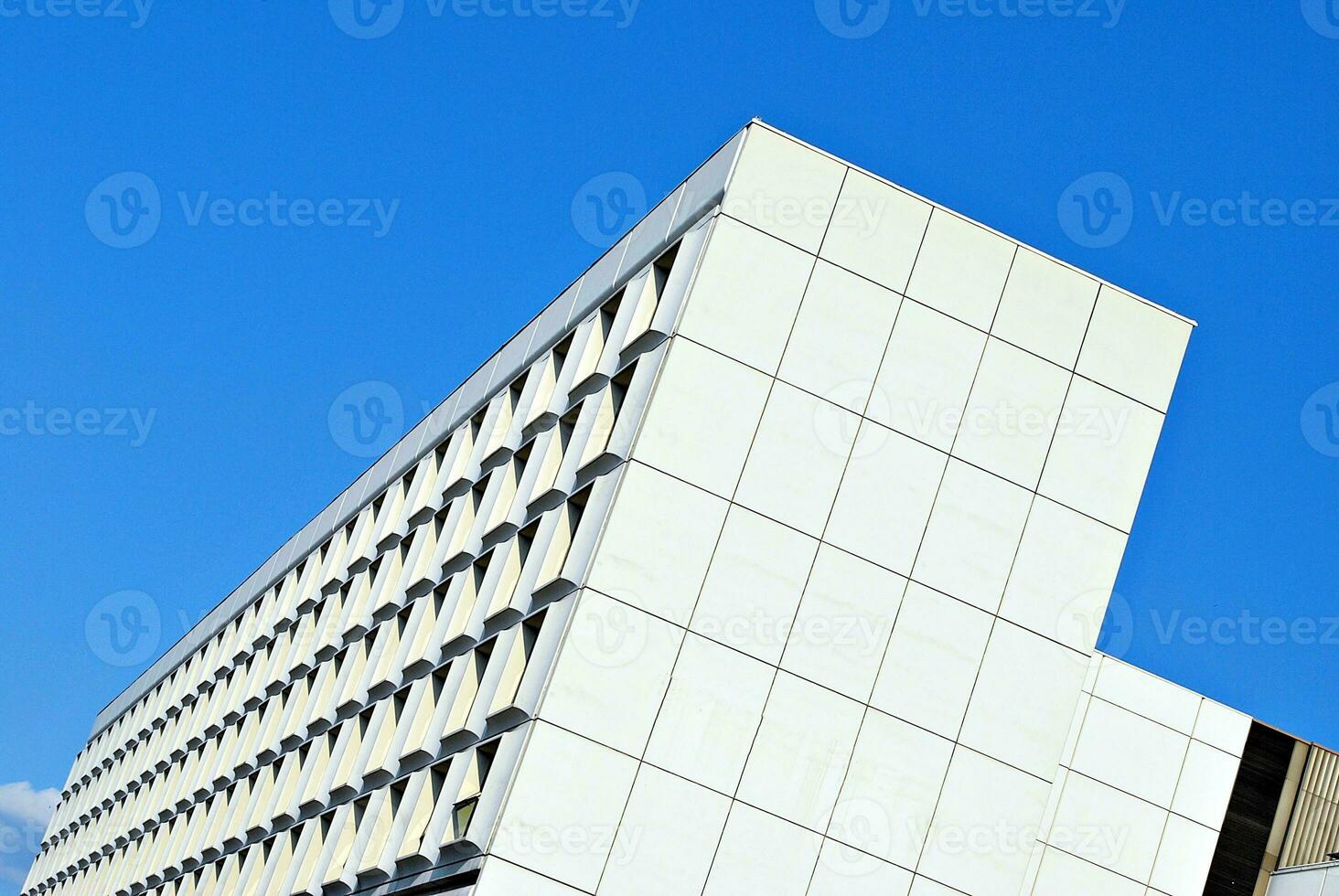 Abstract closeup of the glass-clad facade of a modern building covered in reflective plate glass. Architecture abstract background. Glass wall and facade detail. photo