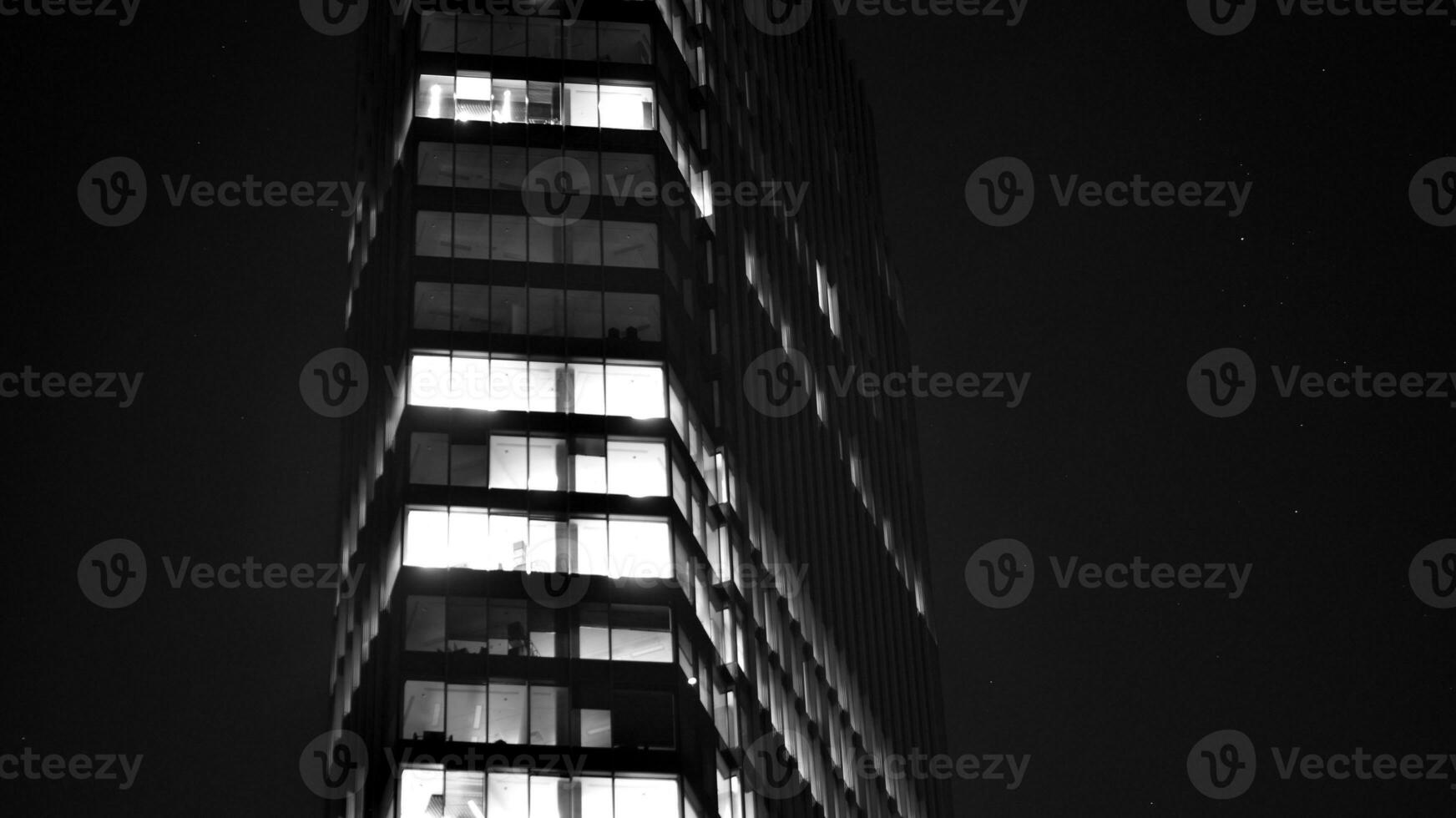 Pattern of office buildings windows illuminated at night. Glass architecture ,corporate building at night - business concept. Black and white. photo