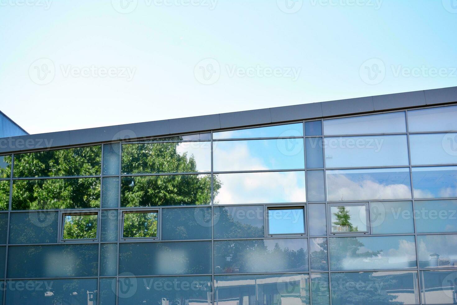 Abstract closeup of the glass-clad facade of a modern building covered in reflective plate glass. Architecture abstract background. Glass wall and facade detail. photo