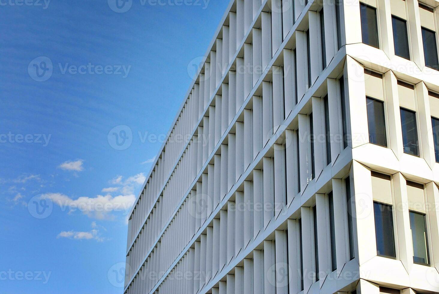 Abstract closeup of the glass-clad facade of a modern building covered in reflective plate glass. Architecture abstract background. Glass wall and facade detail. photo