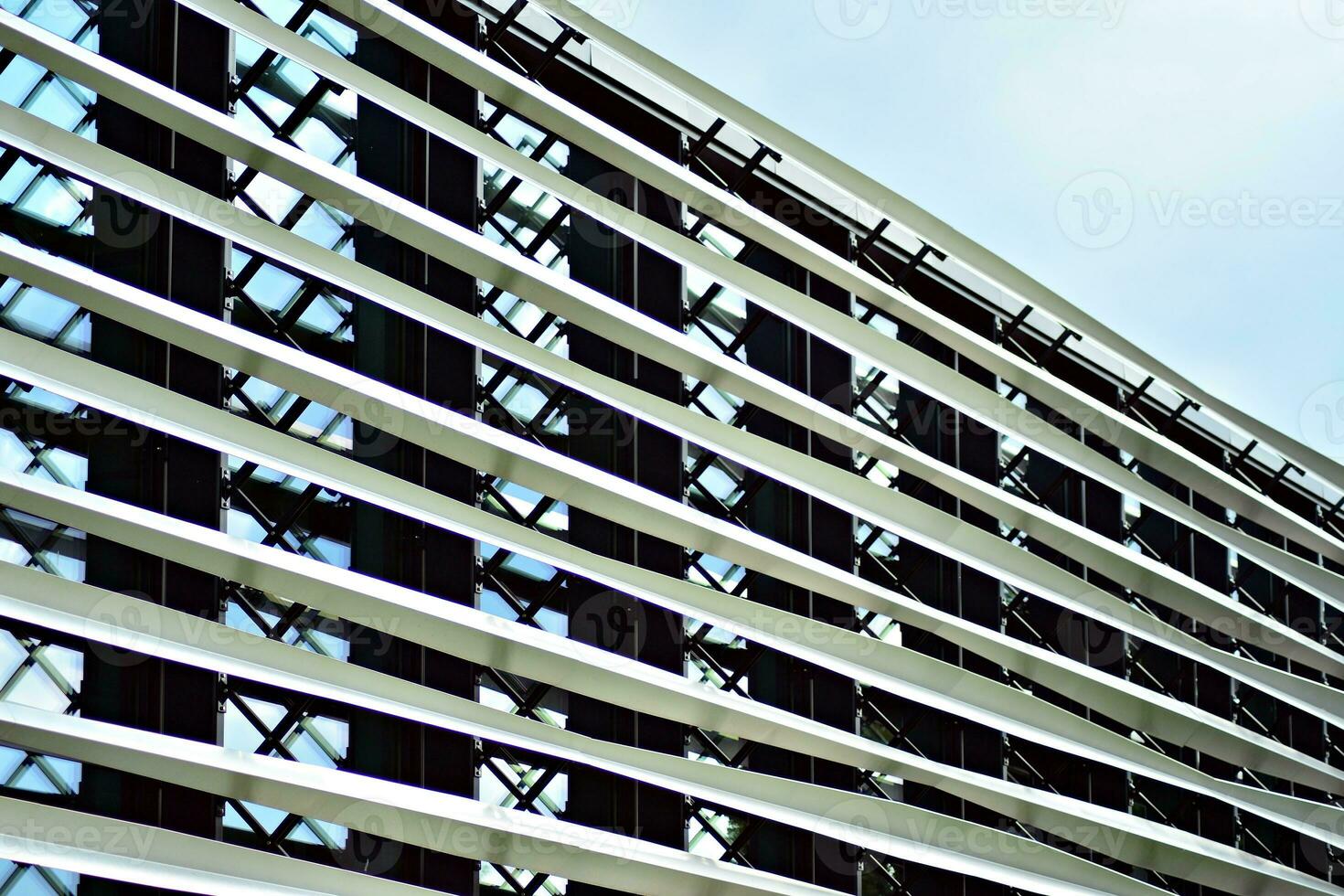 Abstract closeup of the glass-clad facade of a modern building covered in reflective plate glass. Architecture abstract background. Glass wall and facade detail. photo