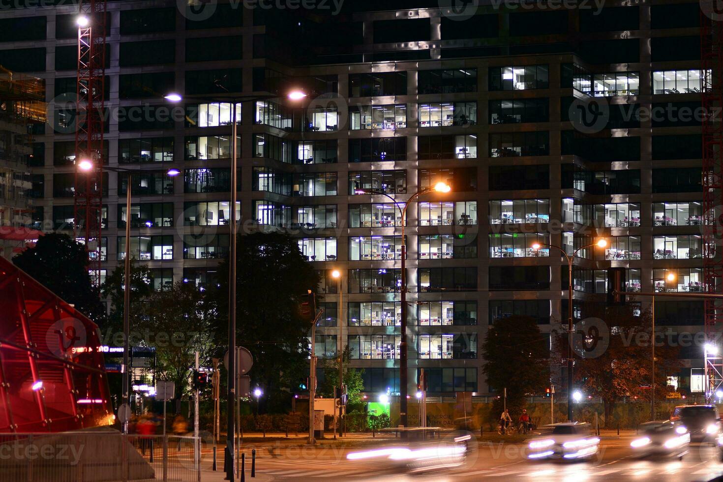 fragmento de el vaso fachada de un moderno corporativo edificio a noche. moderno vaso oficina en ciudad. grande brillante ventanas en moderno oficina edificios a noche, en filas de ventanas ligero brilla foto