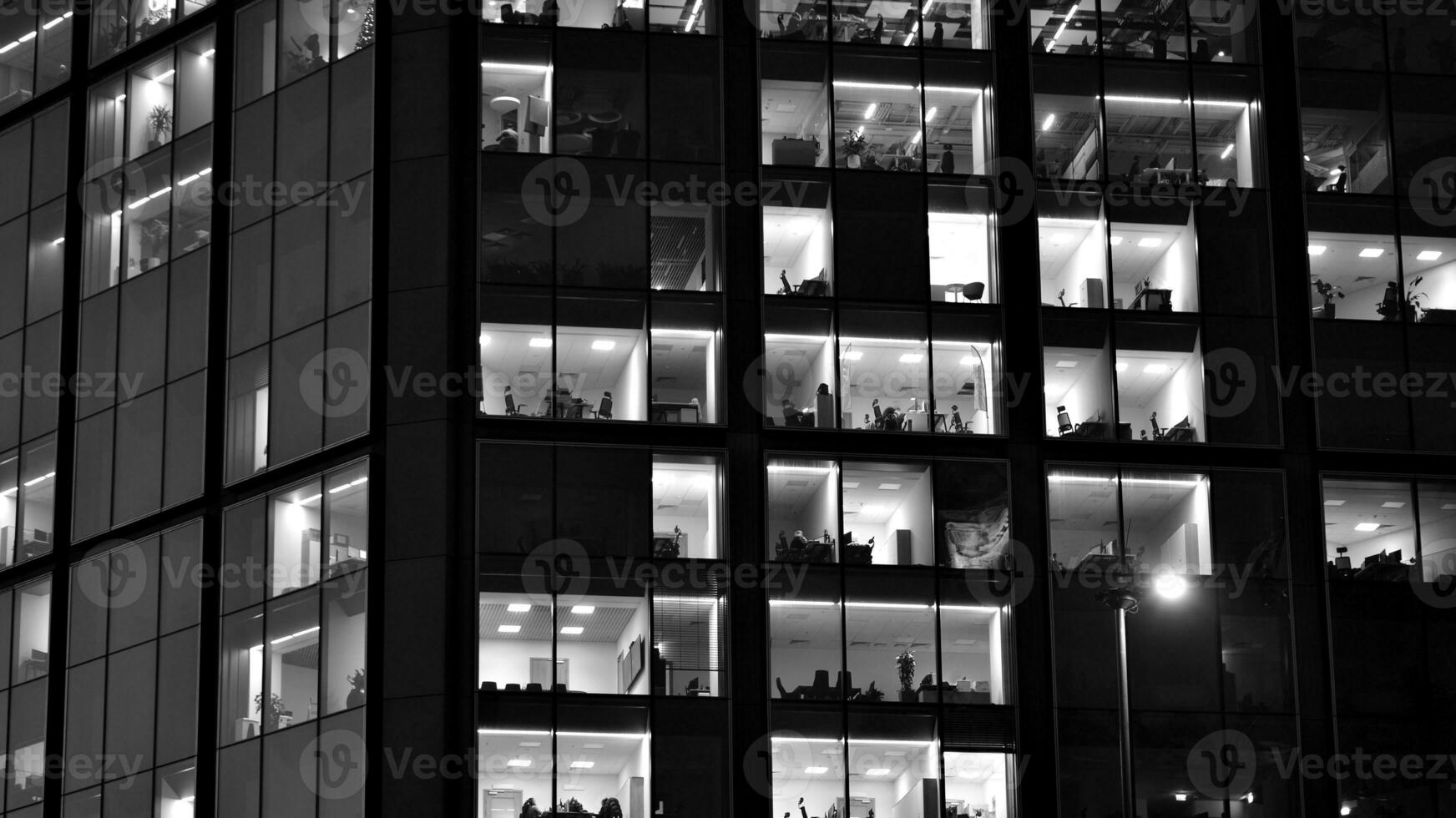 Pattern of office buildings windows illuminated at night. Glass architecture ,corporate building at night - business concept. Black and white. photo