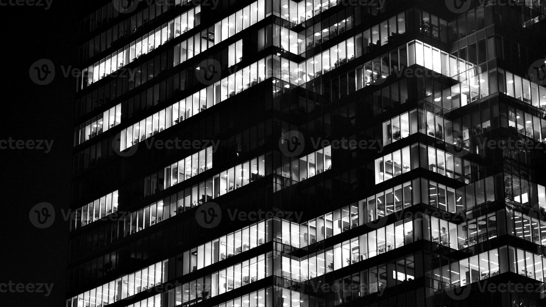 Pattern of office buildings windows illuminated at night. Glass architecture ,corporate building at night - business concept. Black and white. photo