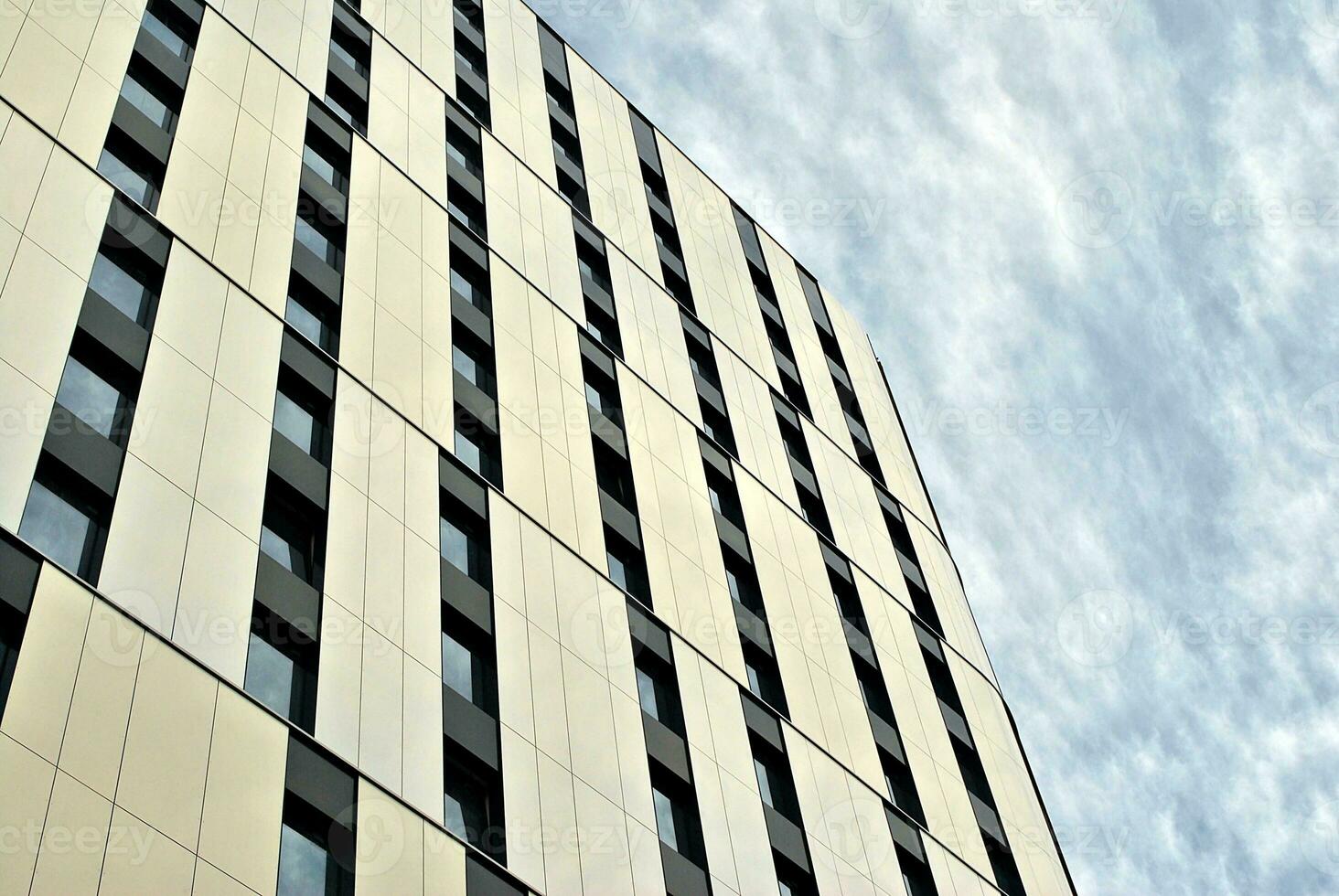 Abstract closeup of the glass-clad facade of a modern building covered in reflective plate glass. Architecture abstract background. Glass wall and facade detail. photo