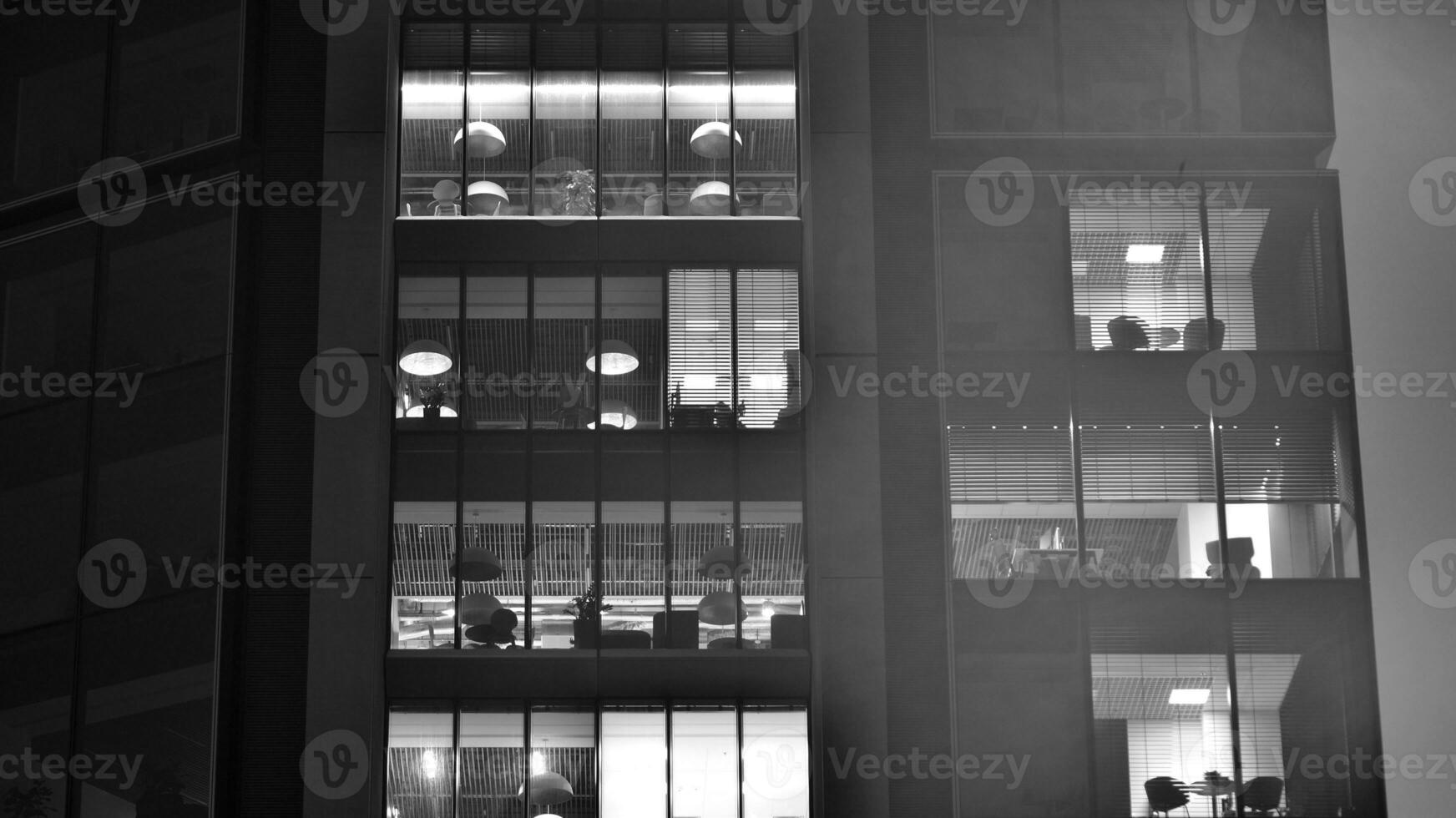 Pattern of office buildings windows illuminated at night. Glass architecture ,corporate building at night - business concept. Black and white. photo