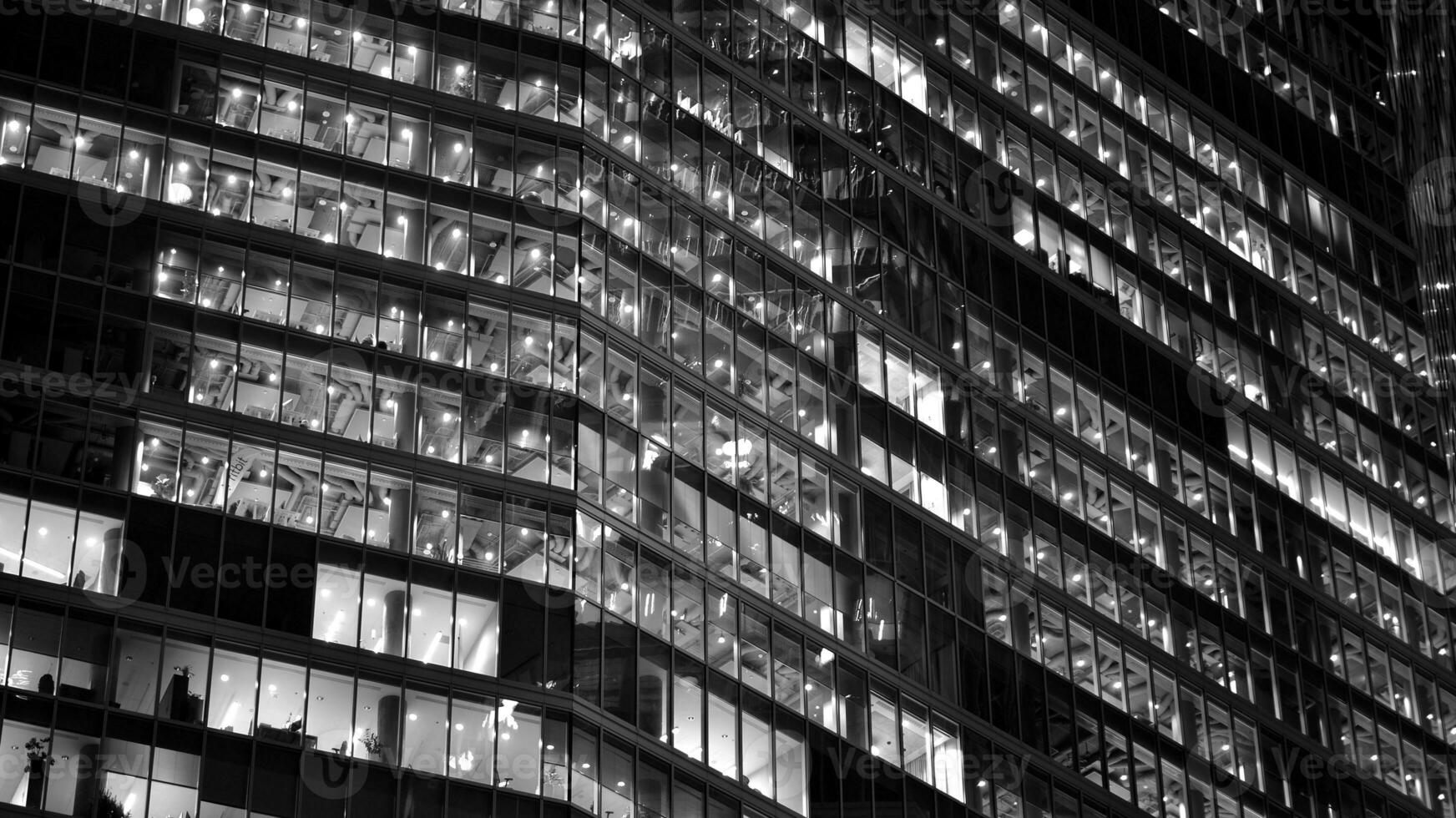 Pattern of office buildings windows illuminated at night. Glass architecture ,corporate building at night - business concept. Black and white. photo