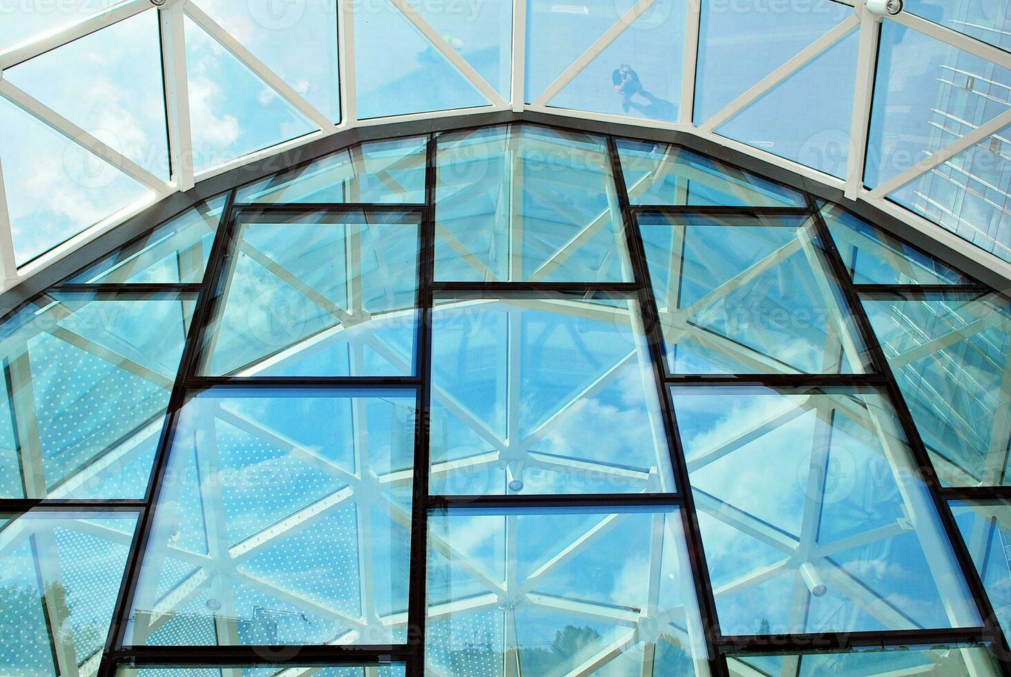 vaso edificio con transparente fachada de el edificio y azul cielo. estructural vaso pared reflejando azul cielo. foto