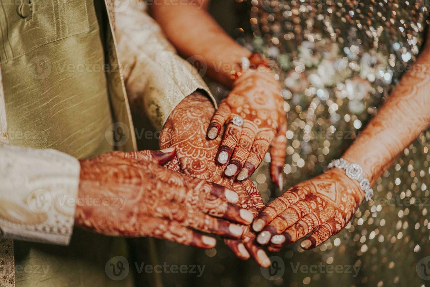 Indian bride and groom hand with henna showing their engagement ring photo