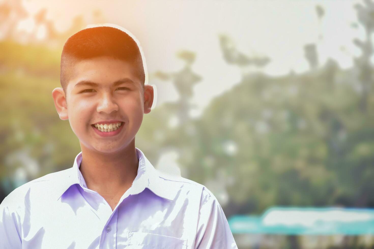 Asian cute schoolboy which has short hair in white school uniform and big smile, soft focus, face and smile expression of human concept. photo