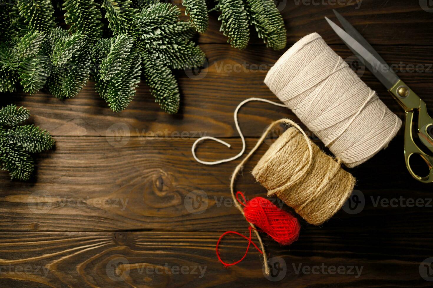 scissors, twisted cotton rope and burlap cord on wooden table decorated with spruce branches photo