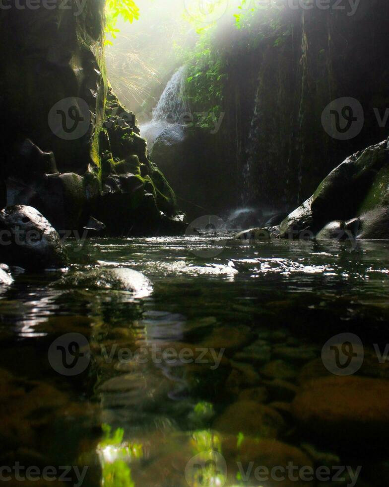 Visit the charm of Indonesia with the Lorong Watu waterfall, North Bengkulu. A narrow alley lined with stone walls, the morning light shines on the waterfall photo