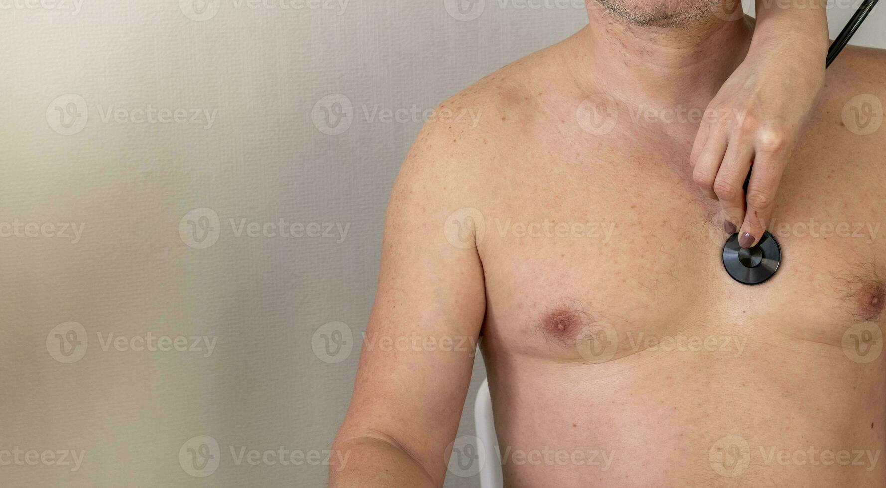 Shot of the female doctor in uniform against the white wall examining mid age male patient. Healthcare photo