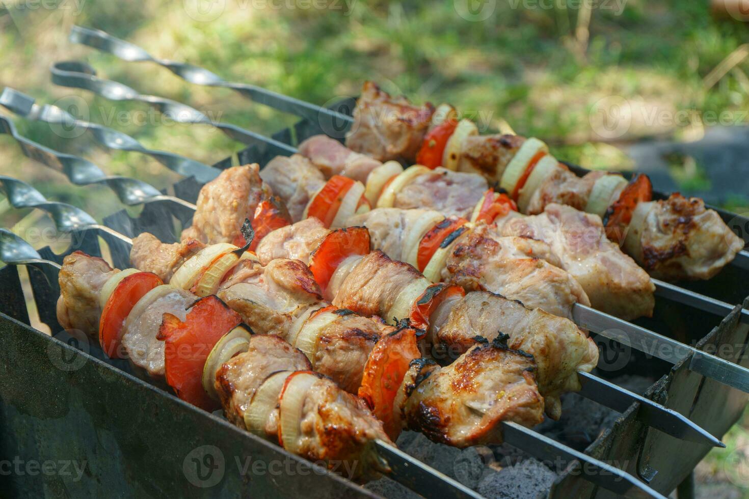 A la parrilla piezas de carne en brochetas, shish brocheta con verduras, Cocinando proceso en brasero foto