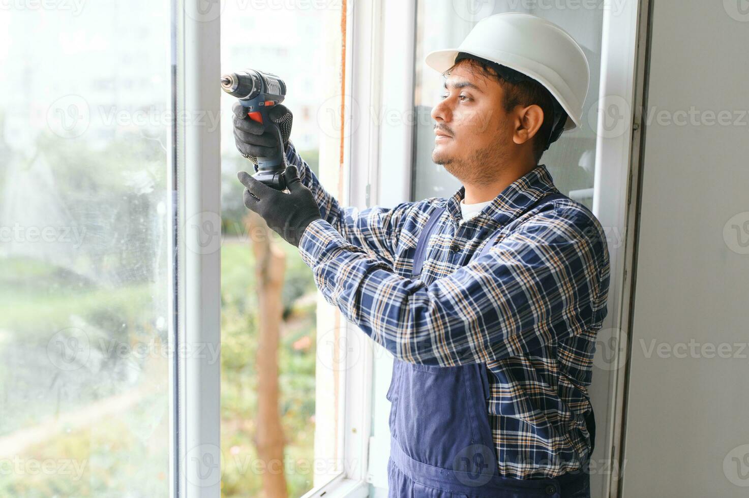 Indian service man installing window with screwdriver photo