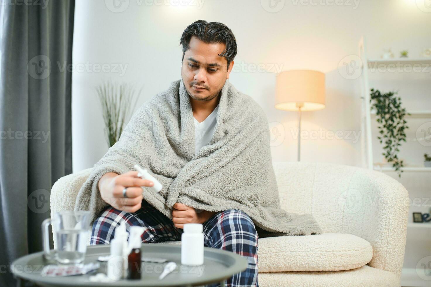 Sick Indian man in plaid sit alone shivering from cold. Unhealthy Arabian guy sit on chair feeling discomfort try to warming up photo