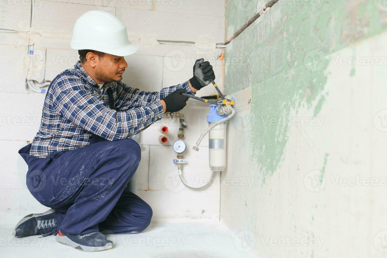 Indian plumber installing water equipment - meter, filter and pressure reducer photo