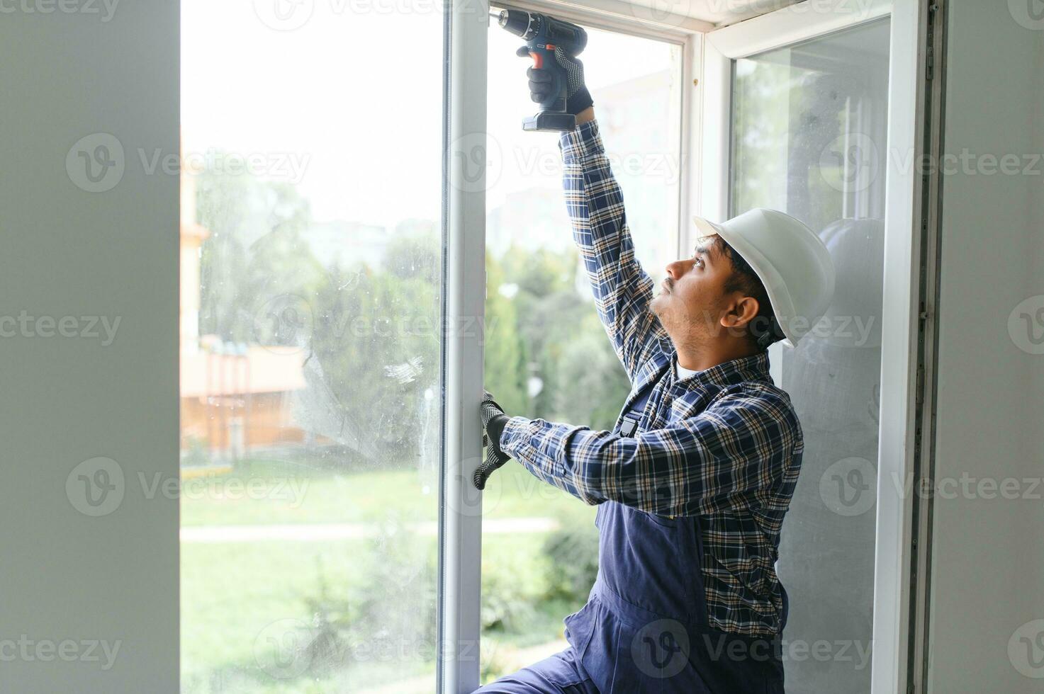 Indian service man installing window with screwdriver photo