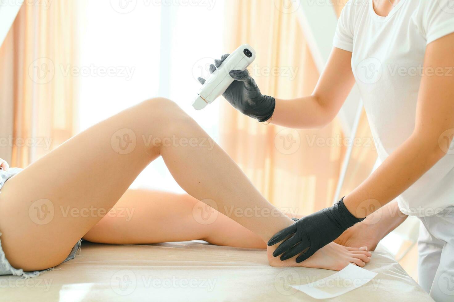 Beautician waxing female legs in spa center photo