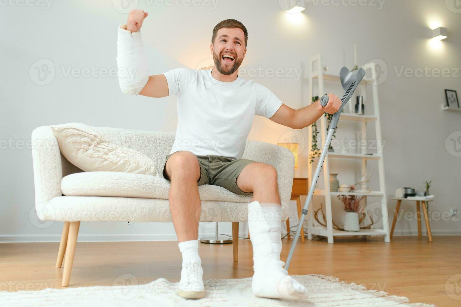 Man with multiple physical limb and body injuries recovers after accident. Happy guy having fun at home photo