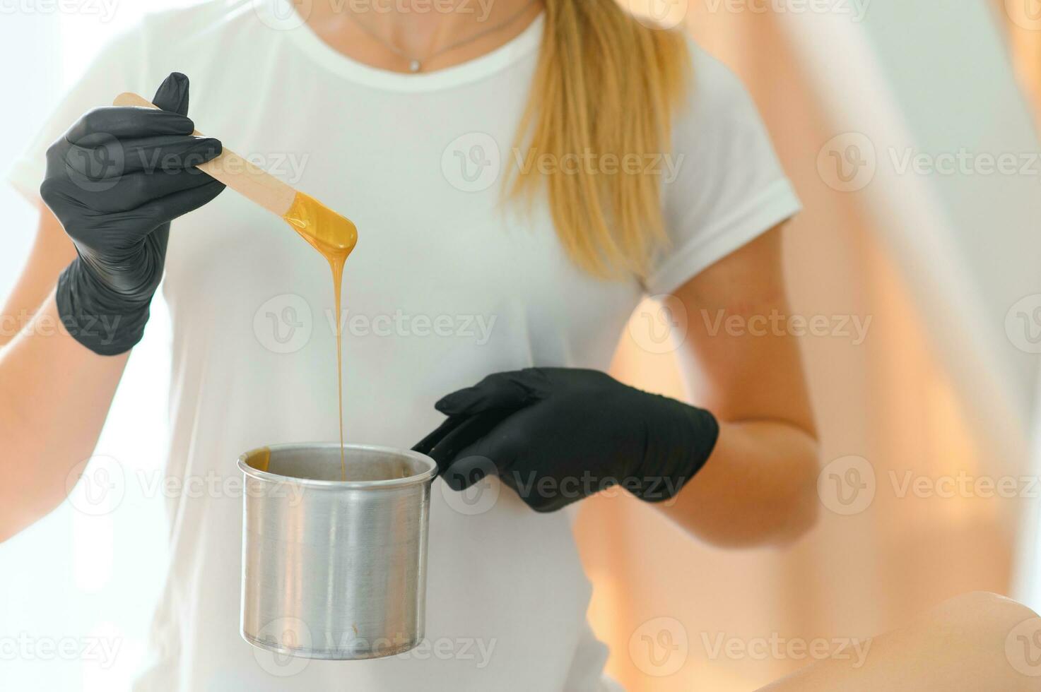 Portrait of a female caucasian beautician holding a jar of sugar paste for sugaring photo