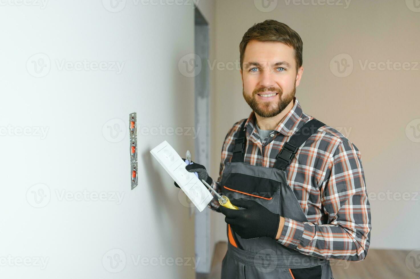 Electrician installs decorative frame on electric and TV sockets photo