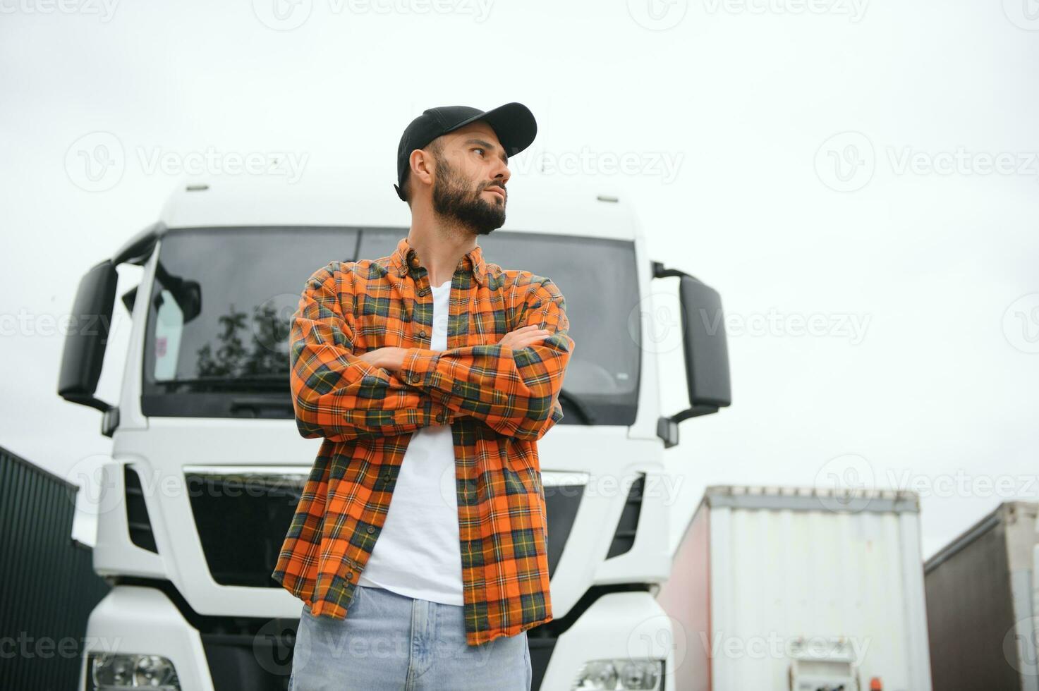Portrait of young bearded trucker standing by his truck vehicle. Transportation service. Truck driver job photo