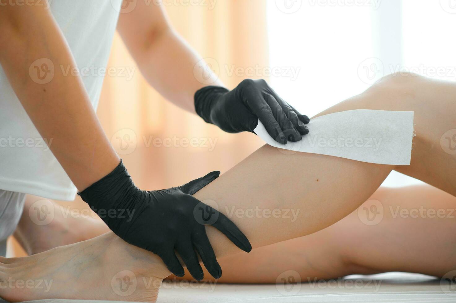 Beautician makes depilation young woman on her feet with wax, liquid sugar photo