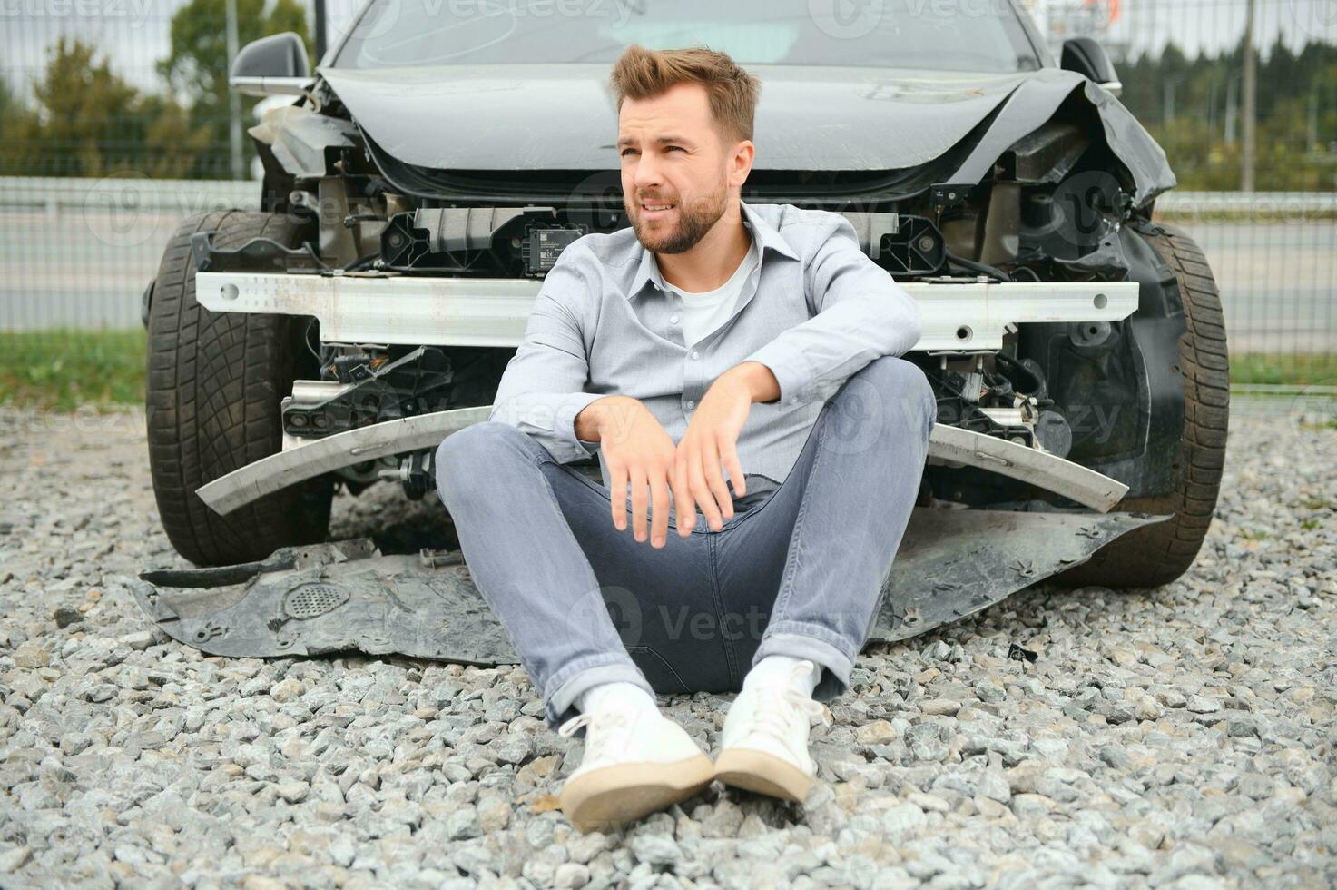 Young man driver in car accident near broken car on the road after a car accident photo