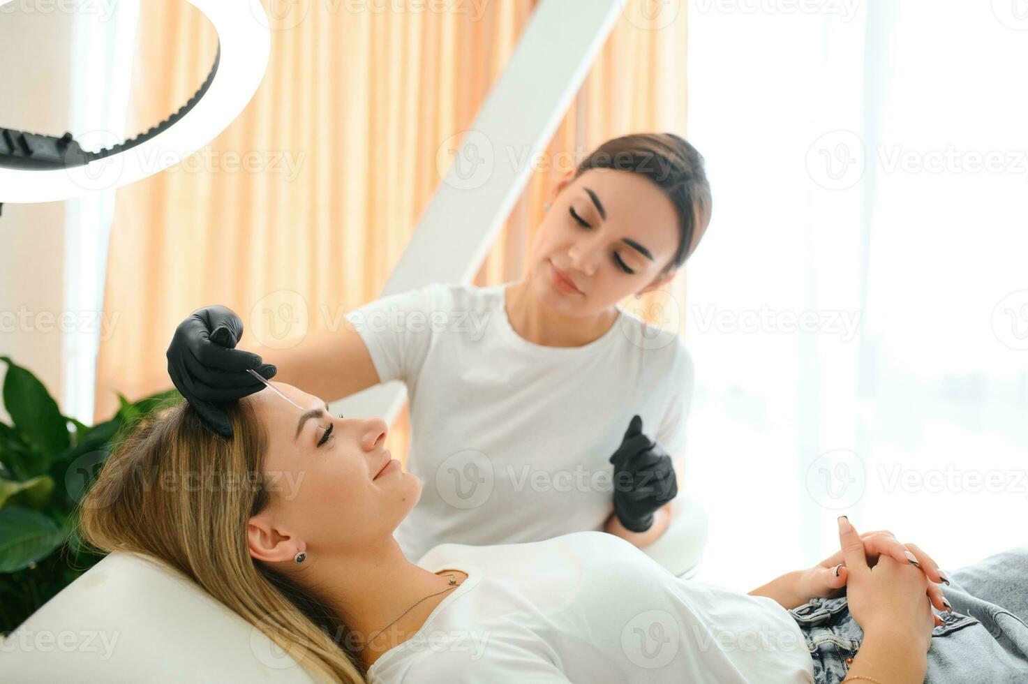 Process of creating permanent brow makeup with a machine at beauty salon photo