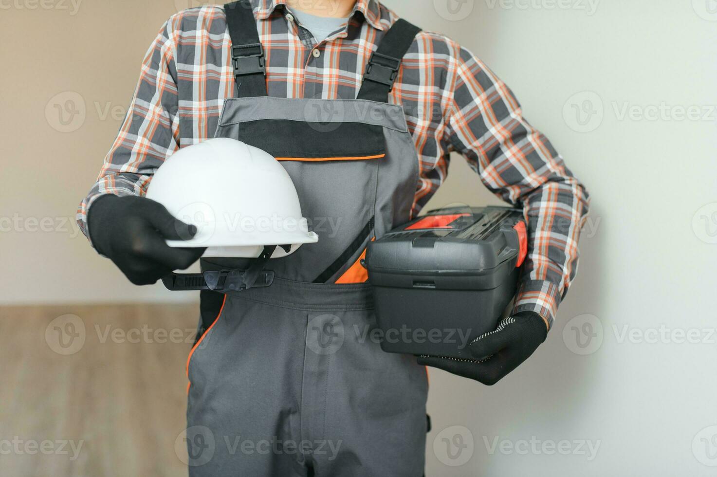 Portrait of positive, handsome young male builder while working at construction site. photo