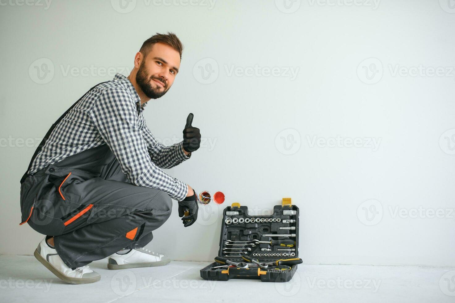 Electrician Builder at work, installation of sockets and switches. Professional in overalls with an electrician's tool. Against the background of the repair site photo