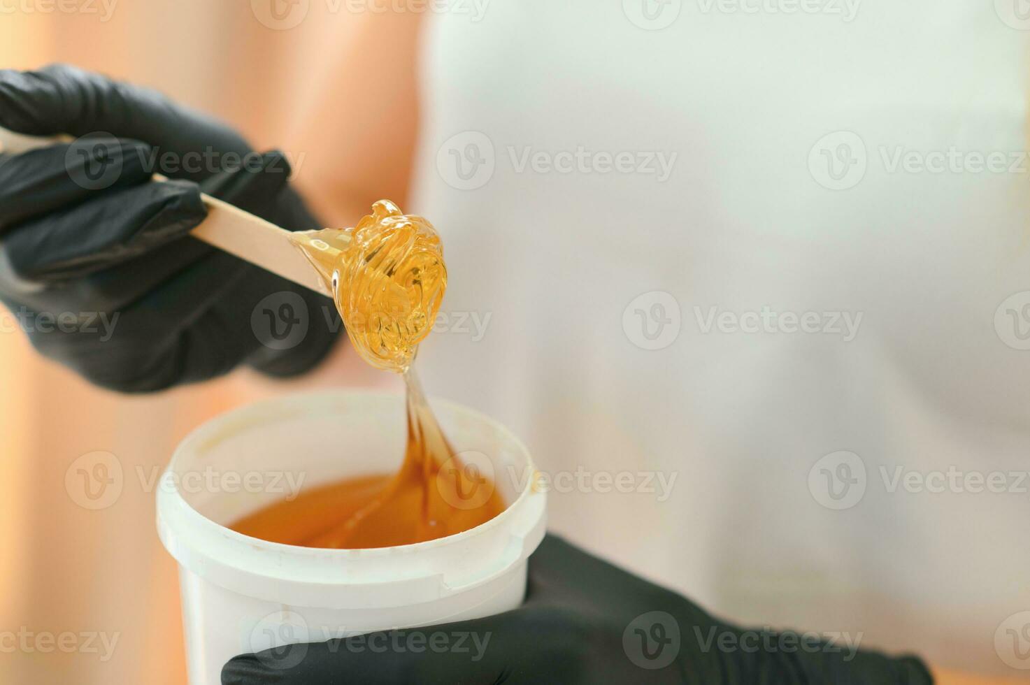 Portrait of a female caucasian beautician holding a jar of sugar paste for sugaring photo