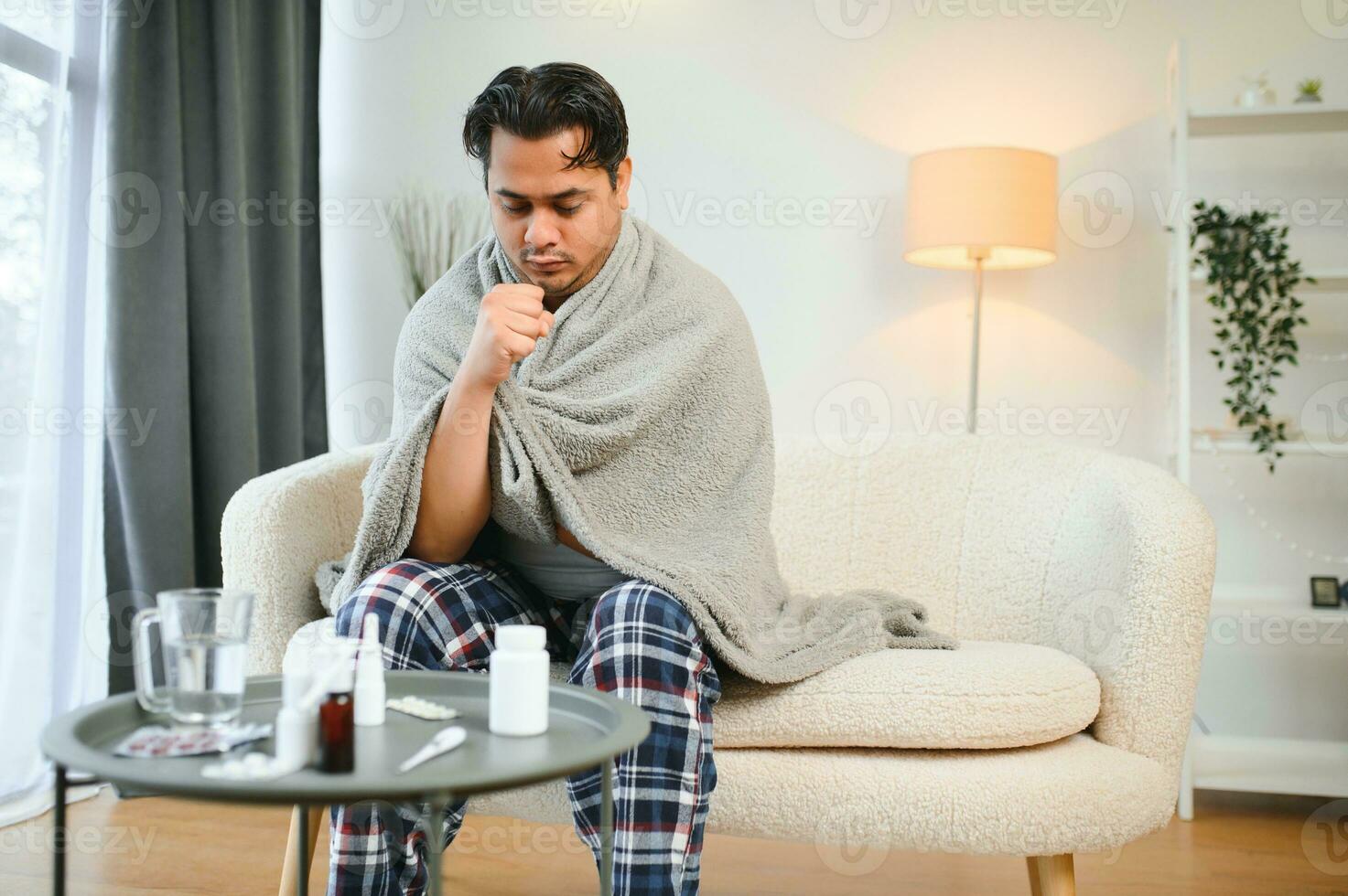 health, cold and people concept - sick young indian man in blanket having headache or fever at home photo