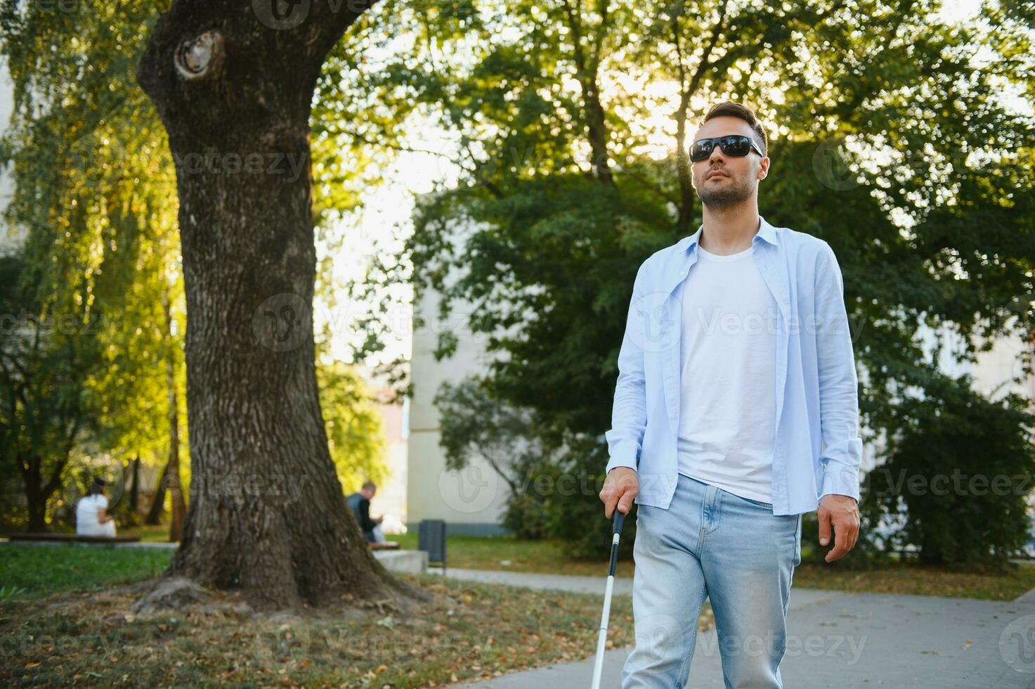 Blind Man Walking On Sidewalk Holding Stick. photo