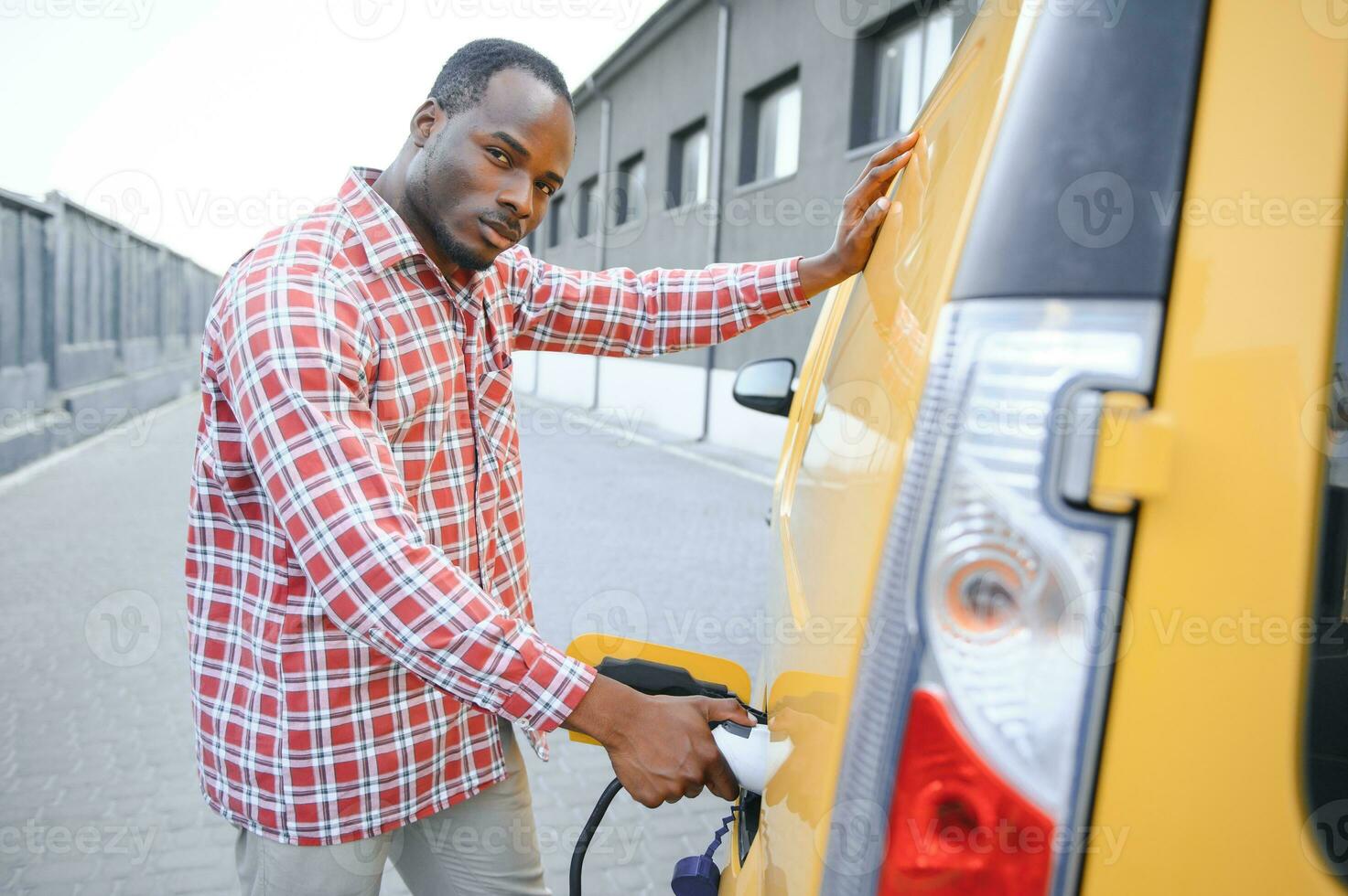 Stylish man inserts the charging cable into the socket of electric car photo