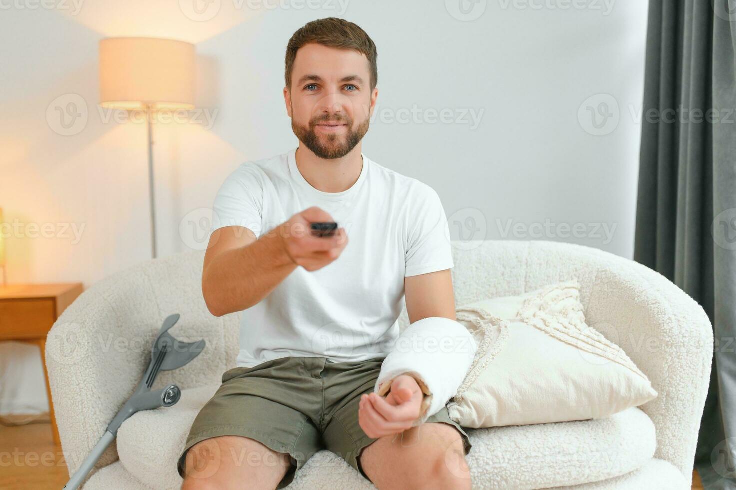 Young man after car accident suffering at home. A man with injuries is watching TV photo