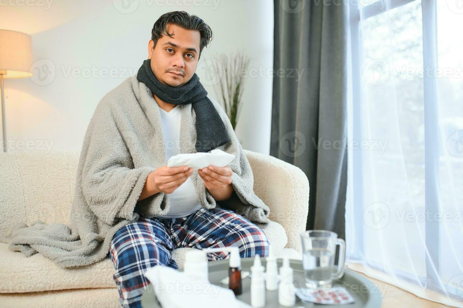 retrato de enfermo indio hombre con líquido nariz participación papel servilletas cerca cara sentado a hogar. gripe, virus, alergia concepto foto