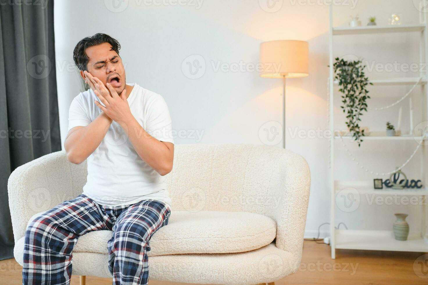 Toothache concept. Sad unhealthy indian or arabian guy touching cheek with hand with painful expression photo