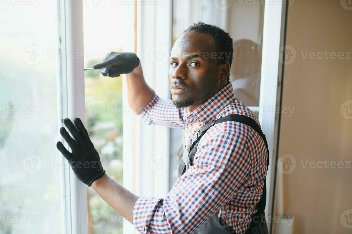 handsome young african american man installing bay window in new house construction site photo