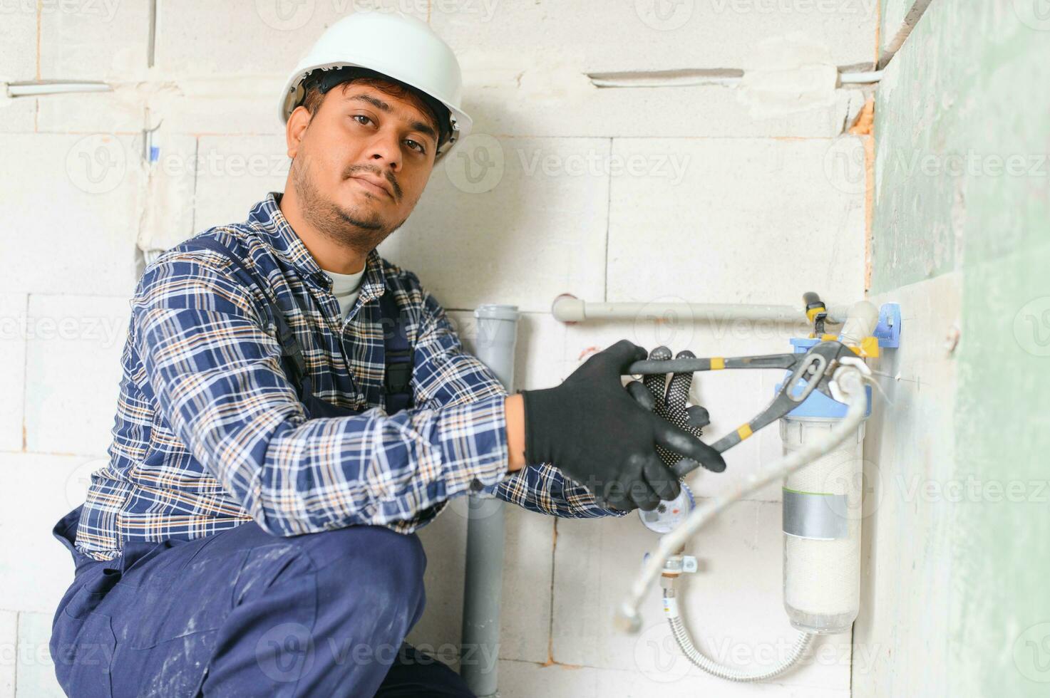 Indian plumber installing water equipment - meter, filter and pressure reducer photo