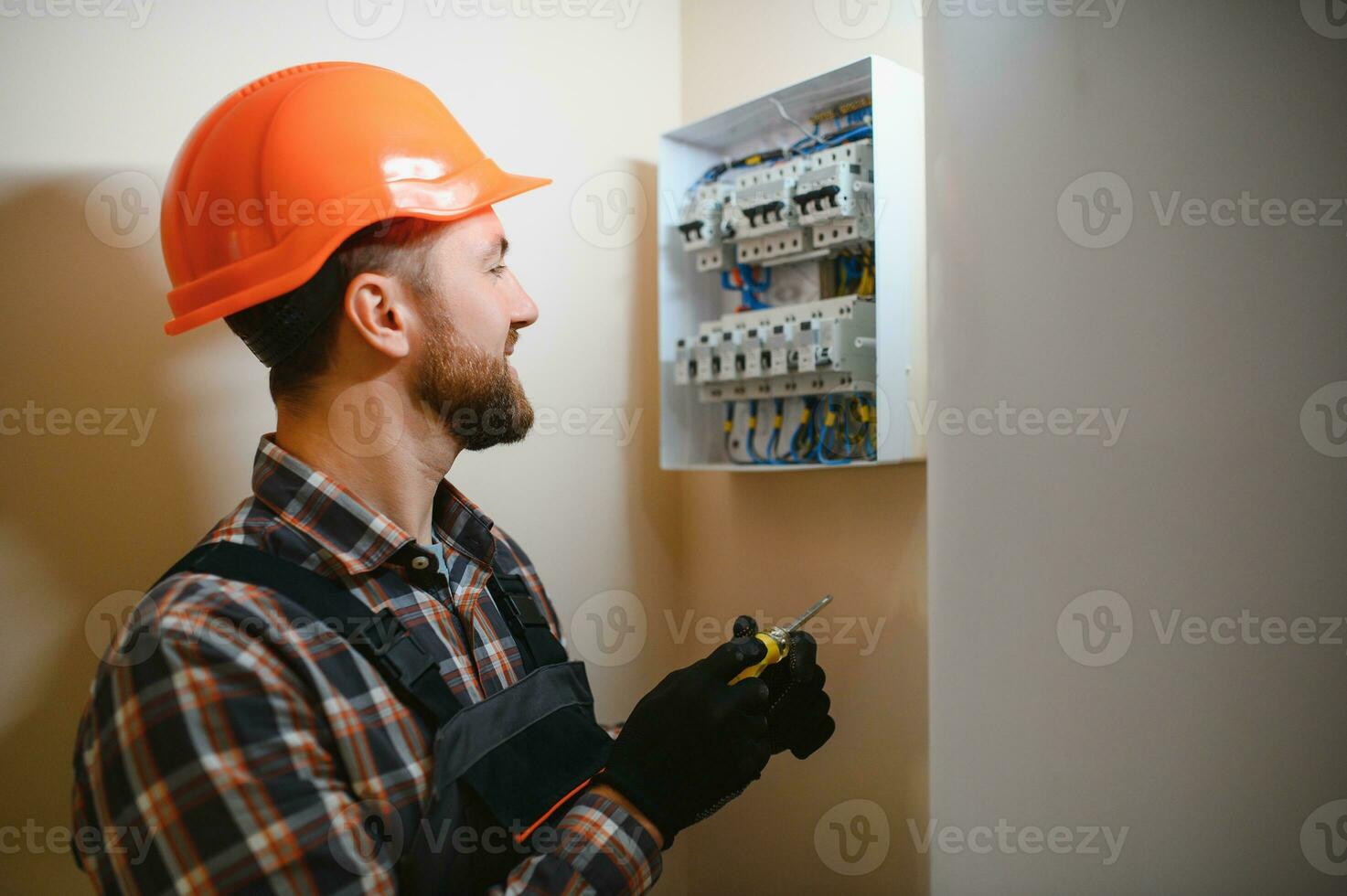 A male electrician works in a switchboard with an electrical connecting cable photo